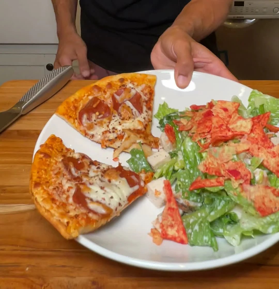 Finished filmed adult plate with two pizza slices and chicken Caesar salad